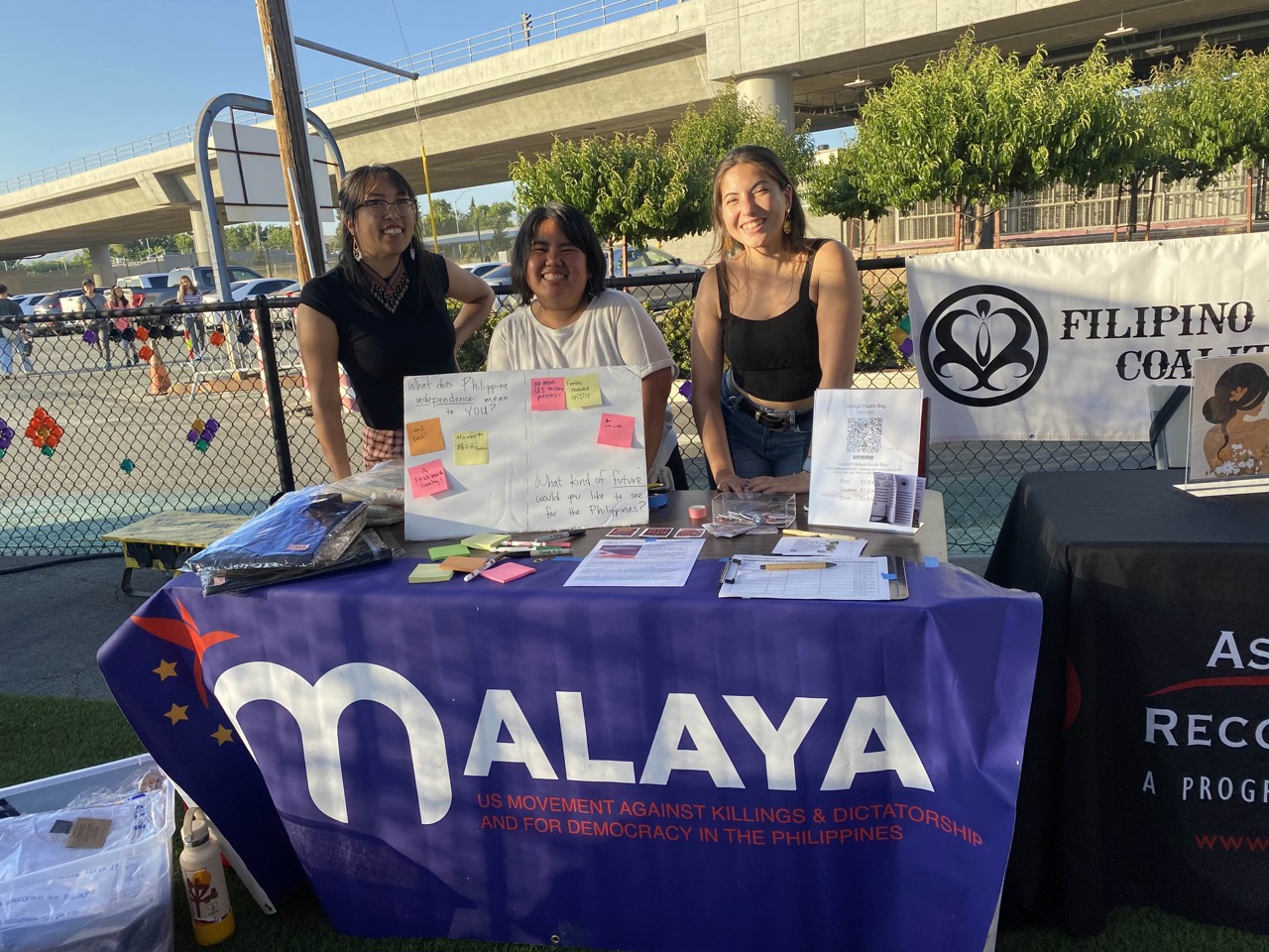 3 malaya members standing at a malaya table at the event