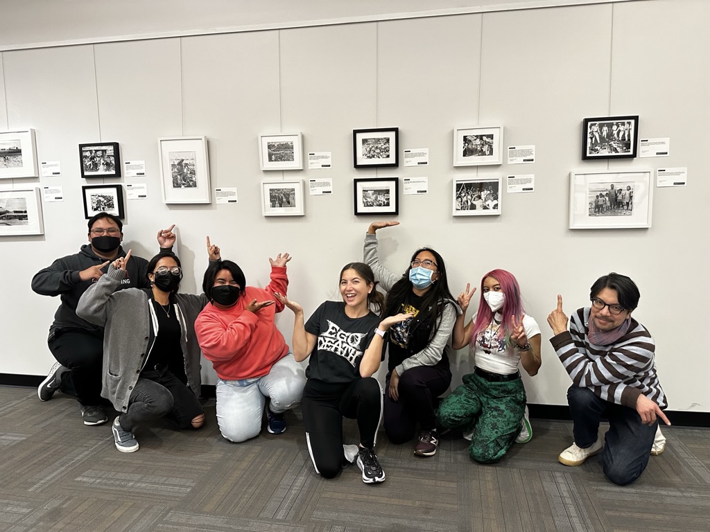 7 adults proudly posing next to a gallery they've installed