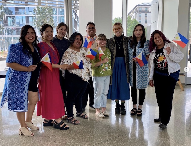 9 adults holding filipino flags and smiling